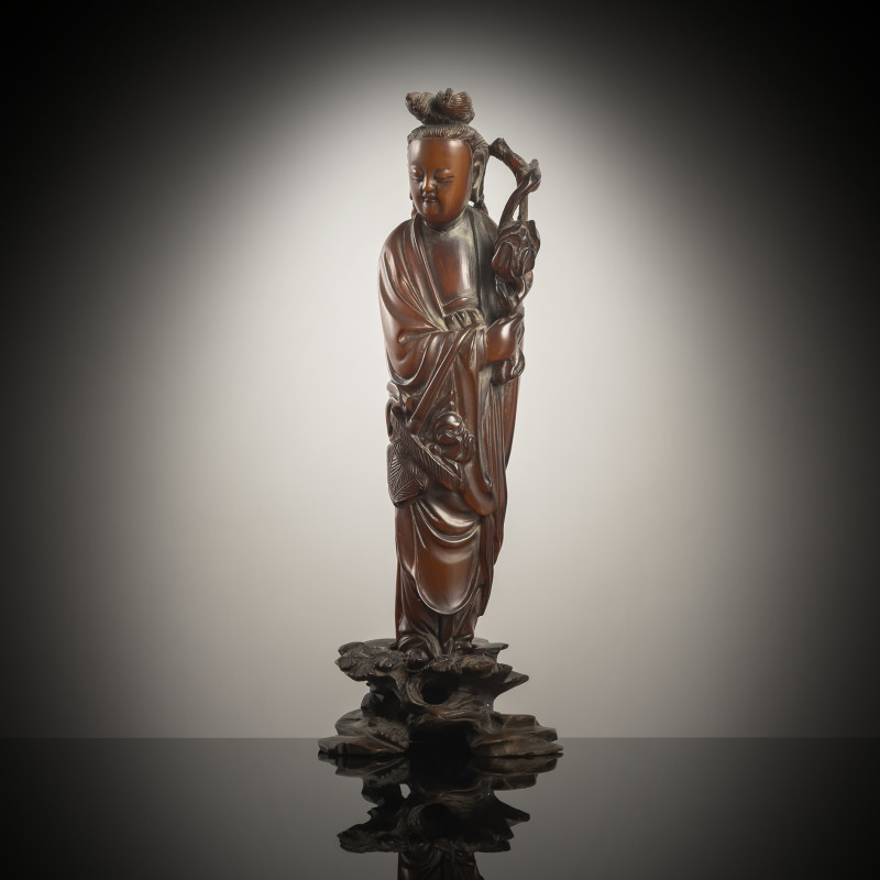 A buffalo horn figure of Guanyin on a wooden stand