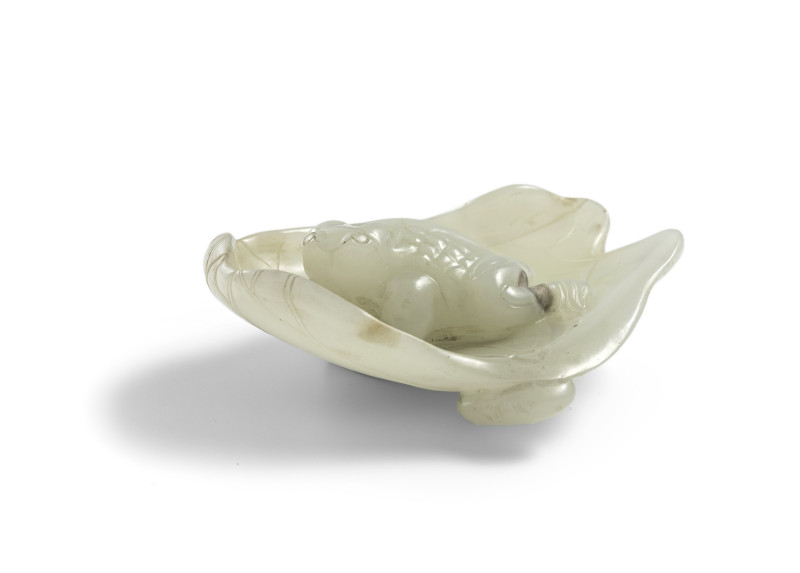 A light green jade carving of a toad in a lotus leaf