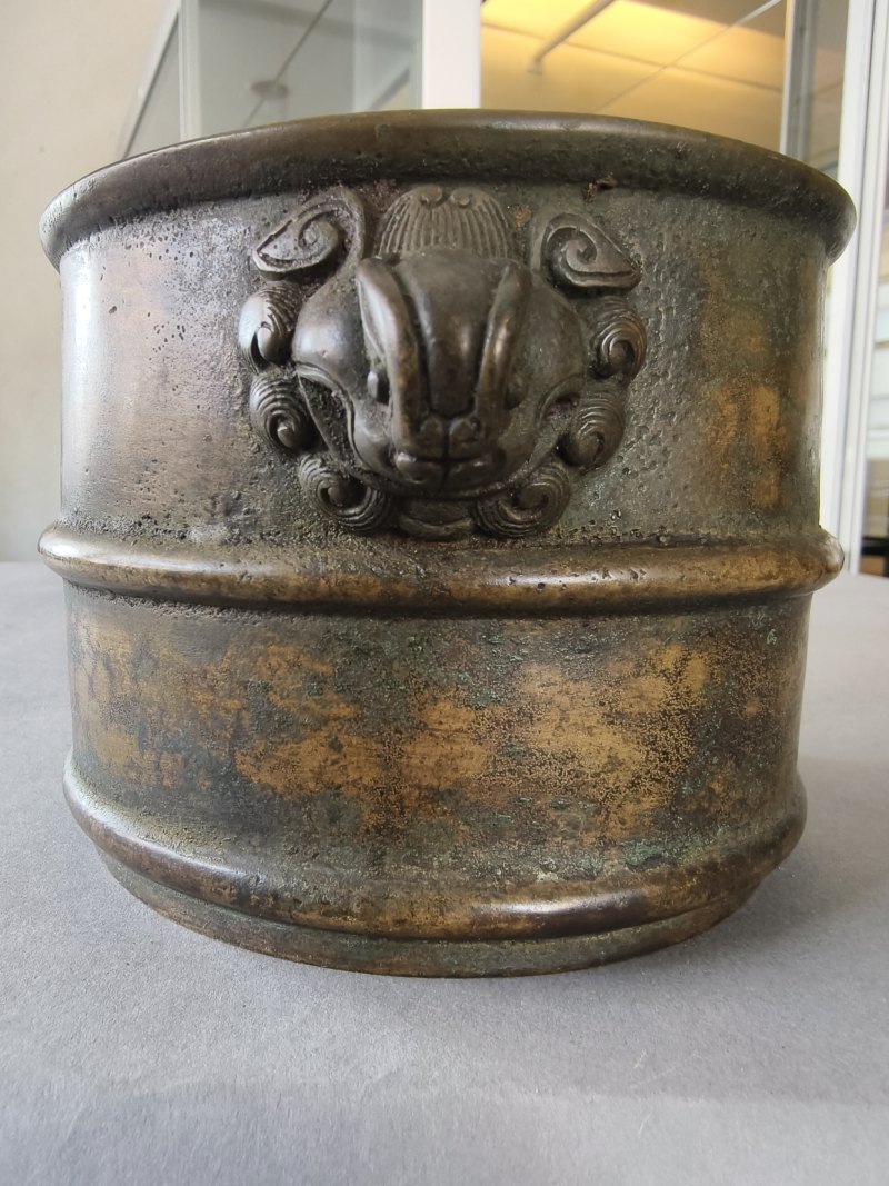 A cylindrical bronze incense burner in the shape of a cylindrical 'Lian' with relief burrs and mask handles on the sides - 图11