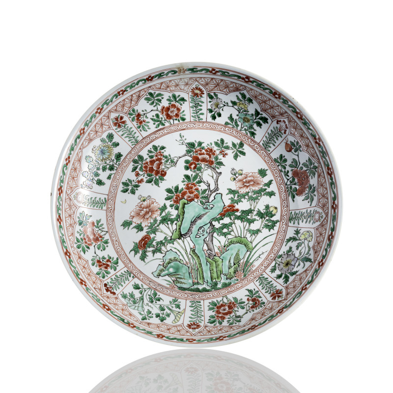 A large porcelain platewith Wucai decoration of peonies and other flowers next to rocks