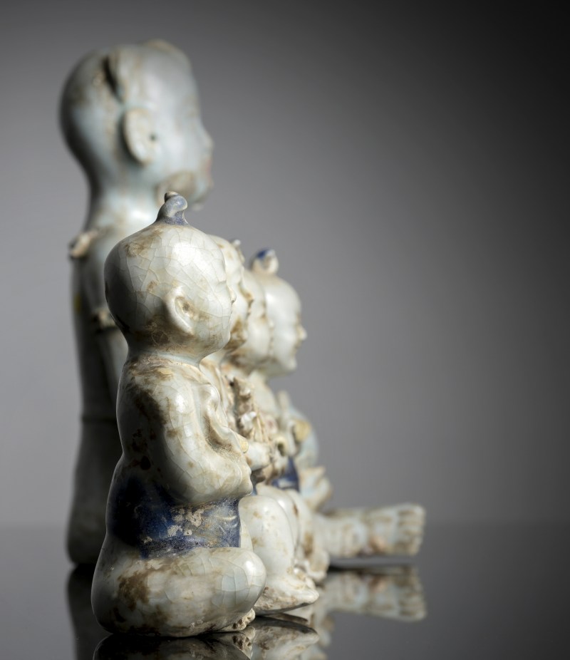 A large 'qingbai' style porcelain sculpture of a boy holding a fish and four small boys - 图4
