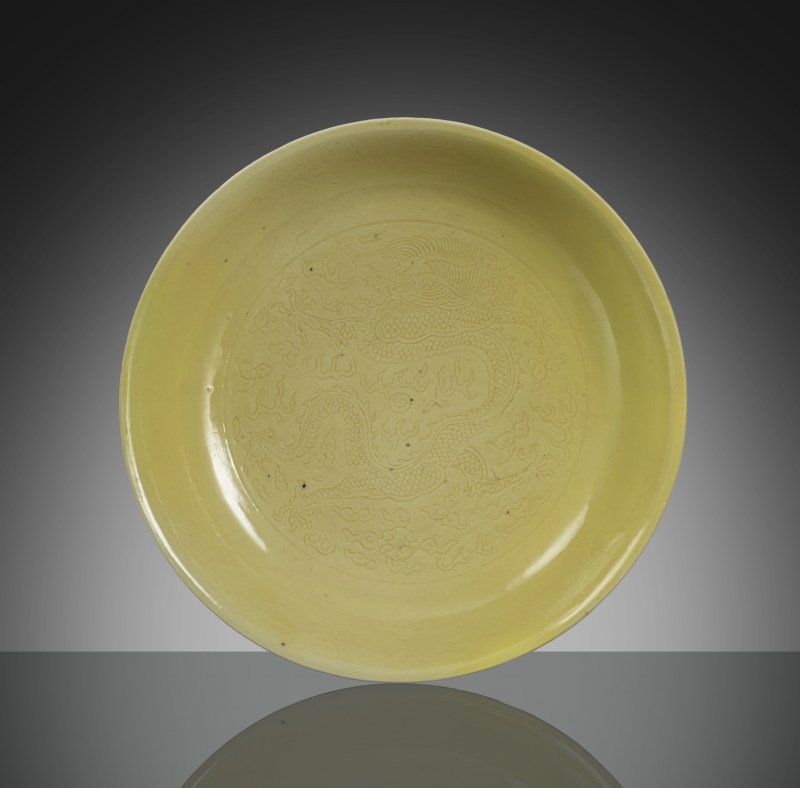 An imperial yellow glazed porcelain plate with engraved decoration of dragons and flaming pearls