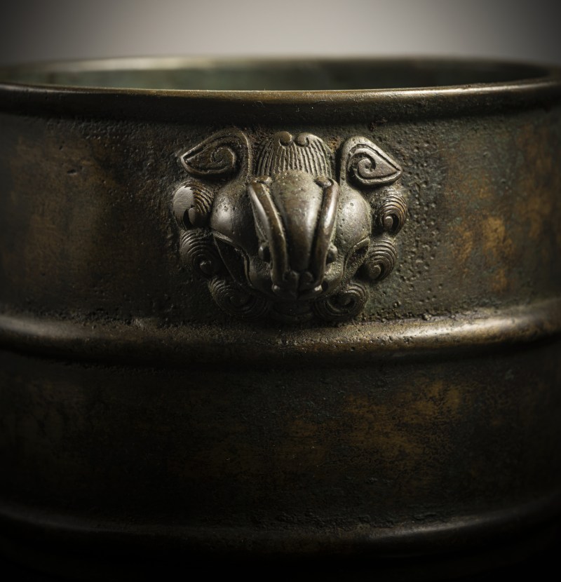 A cylindrical bronze incense burner in the shape of a cylindrical 'Lian' with relief burrs and mask handles on the sides - 图4