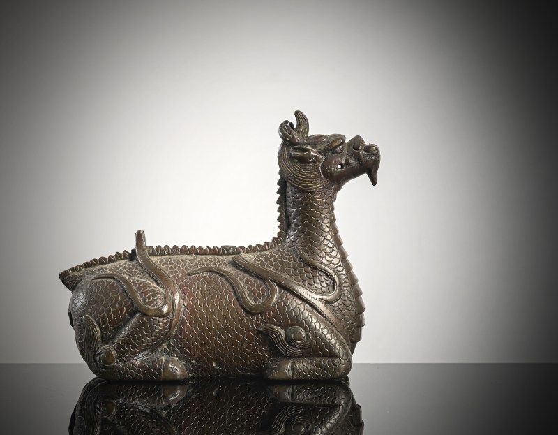 A bronze of a reclining mythical creature on a wooden stand - 图3