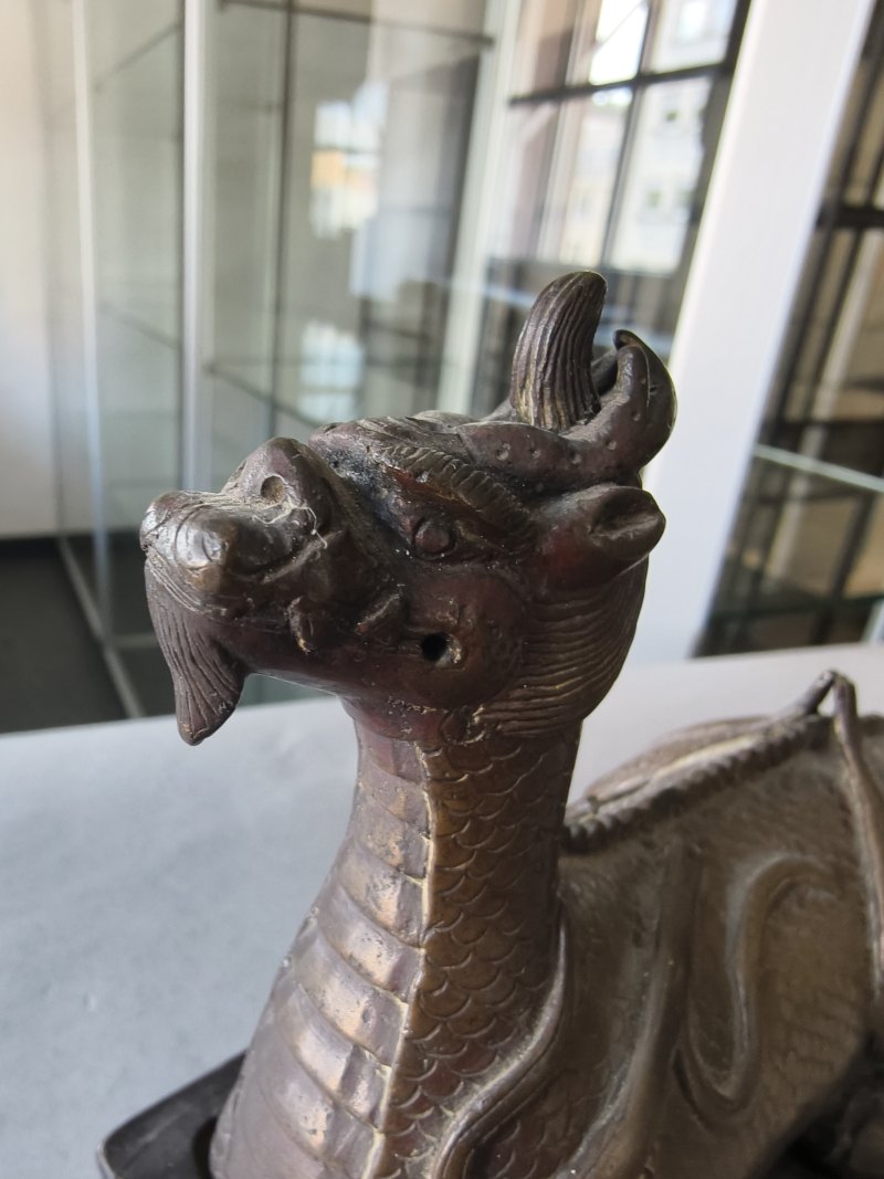 A bronze of a reclining mythical creature on a wooden stand - 图16