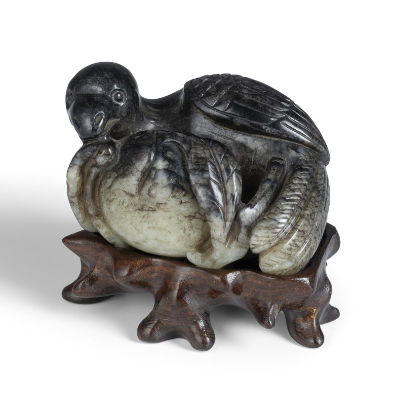 A jade carving of a parrot with fruit in green and black colouring