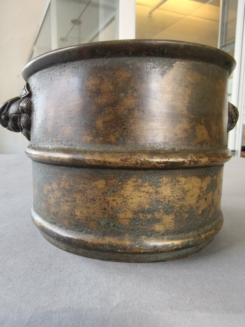 A cylindrical bronze incense burner in the shape of a cylindrical 'Lian' with relief burrs and mask handles on the sides - 图12