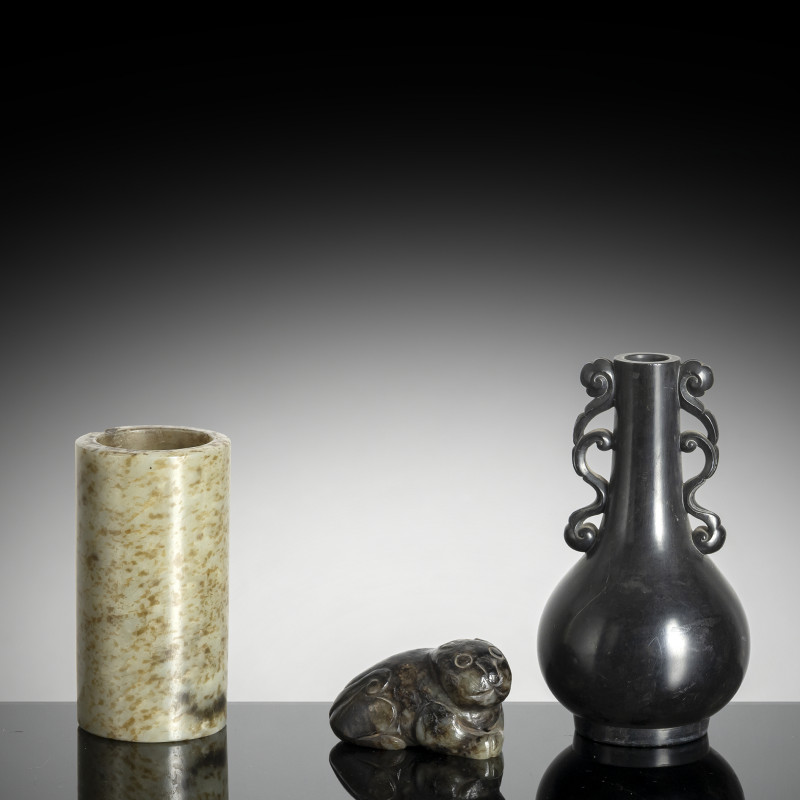 A black stone vase, a cylindrical jade cup and a jade carving of a mythical creature
