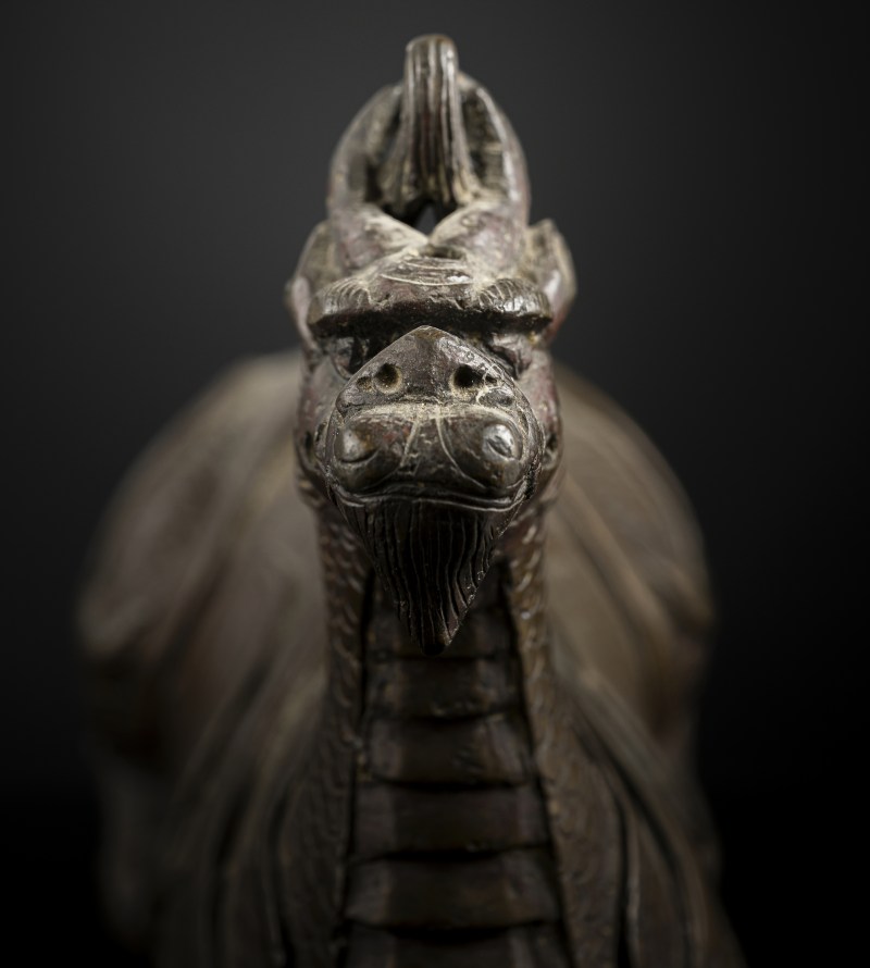 A bronze of a reclining mythical creature on a wooden stand - 图4