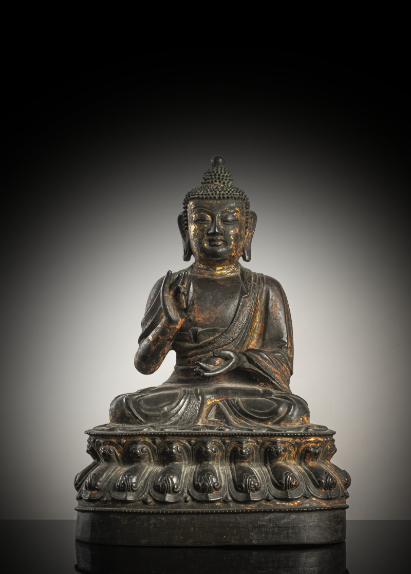 A bronze figure of Buddha Shakyamuni on a lotus throne with remnants of gilding