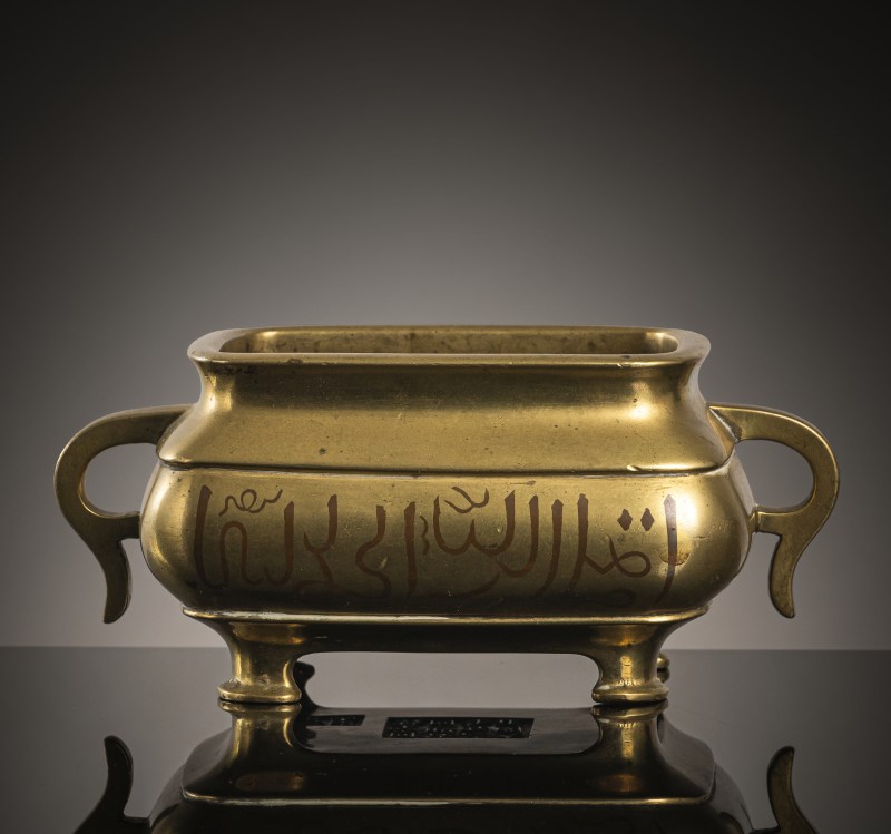 A gold-colored bronze censer on four legs with copper-inlaid Arabic inscription