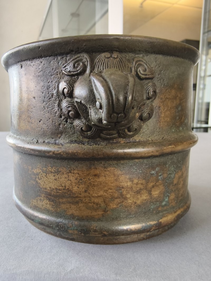 A cylindrical bronze incense burner in the shape of a cylindrical 'Lian' with relief burrs and mask handles on the sides - 图13