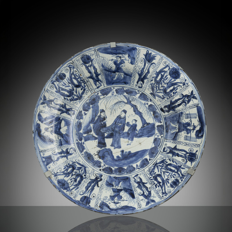 A large blue and white 'Kraak' charger with decoration of scholars and servant boy and reserves with tulips and flowers