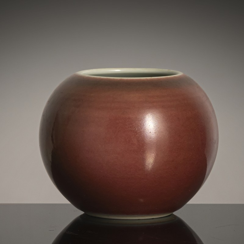 A copper-red spherical porcelain brush washer