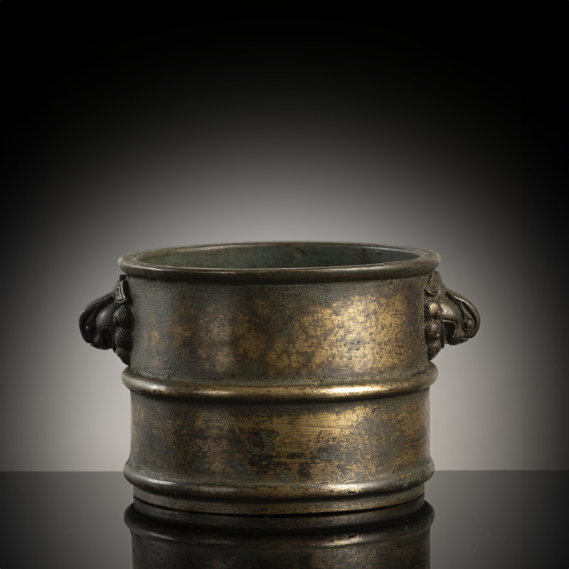 A cylindrical bronze incense burner in the shape of a cylindrical 'Lian' with relief burrs and mask handles on the sides