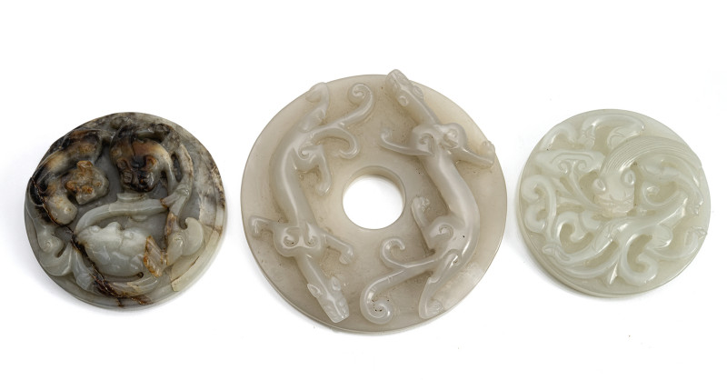 Three bi with sculpted jade chilong, partly in a brown-caramel colour