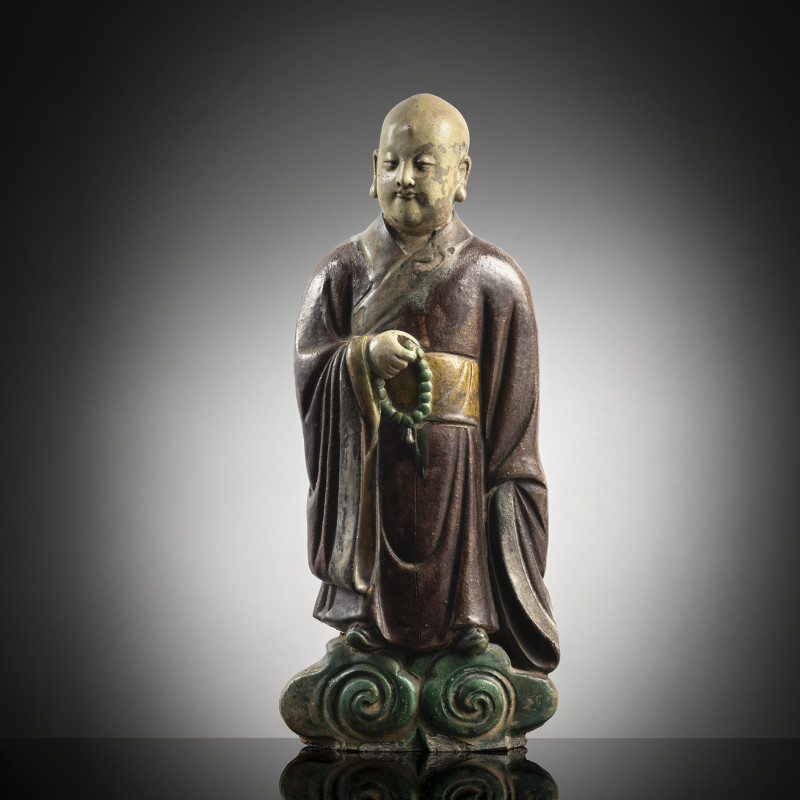 A ceramic figure of a standing monk