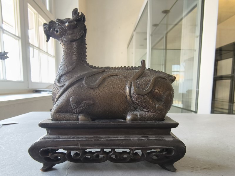 A bronze of a reclining mythical creature on a wooden stand - 图11