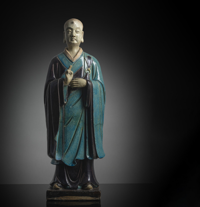 A large pottery figure of a standing Luohan with tricolour glaze, right hand raised