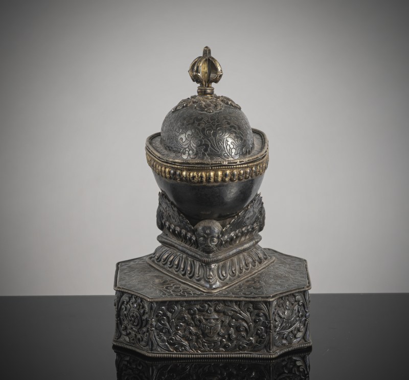 AN EMBOSSED PARCEL GILT SILVER KAPALA ON STAND
