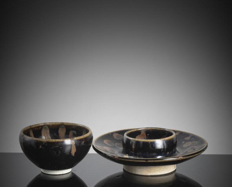 A black-glazed russet-splashed tea bowl on an associated base