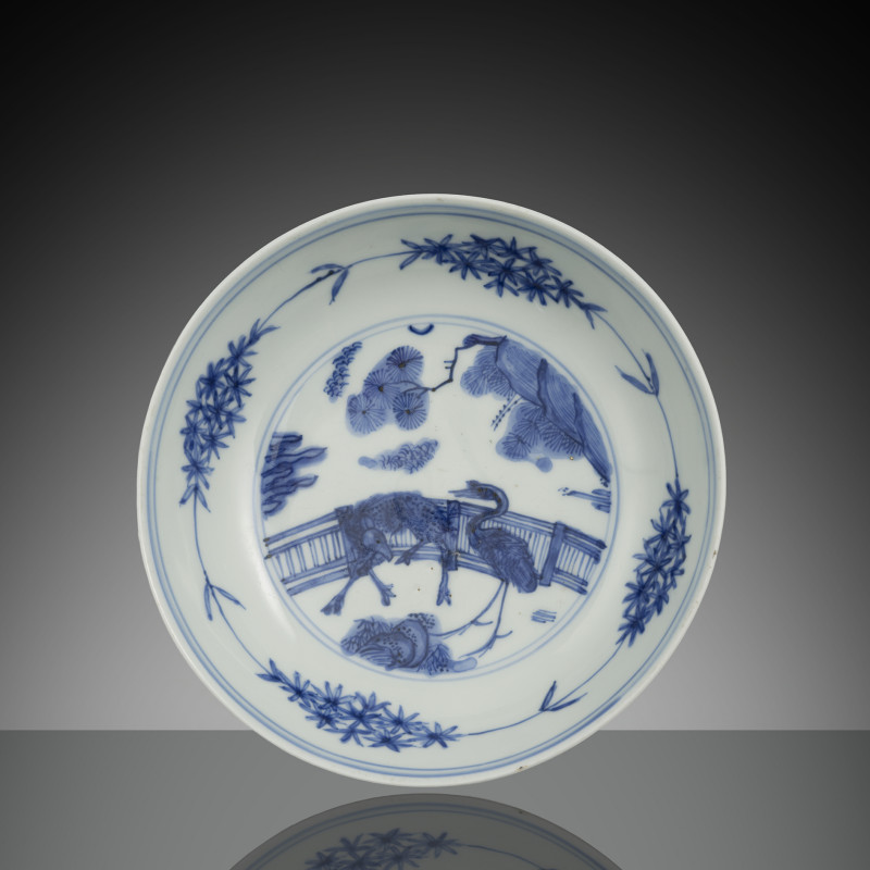 A blue and white porcelain round bowl with crane and deer decoration on a fence
