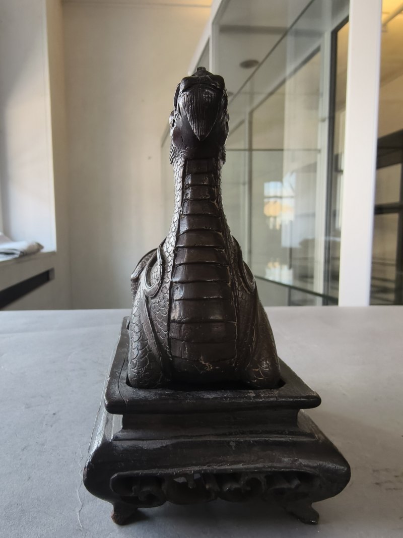 A bronze of a reclining mythical creature on a wooden stand - 图12