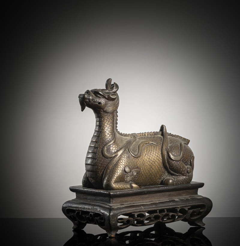 A bronze of a reclining mythical creature on a wooden stand
