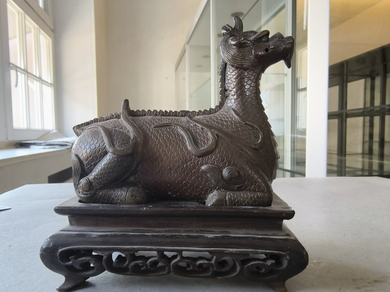 A bronze of a reclining mythical creature on a wooden stand - 图13