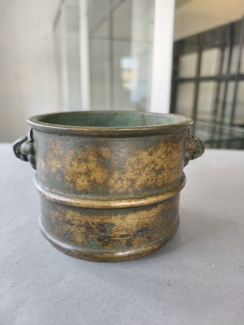 A cylindrical bronze incense burner in the shape of a cylindrical 'Lian' with relief burrs and mask handles on the sides - 图9