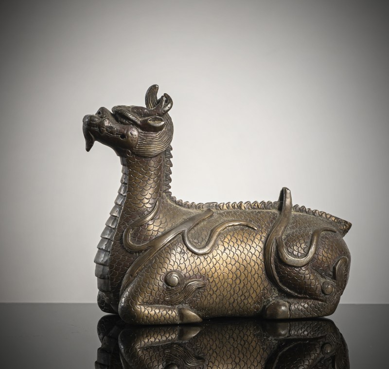 A bronze of a reclining mythical creature on a wooden stand - 图2