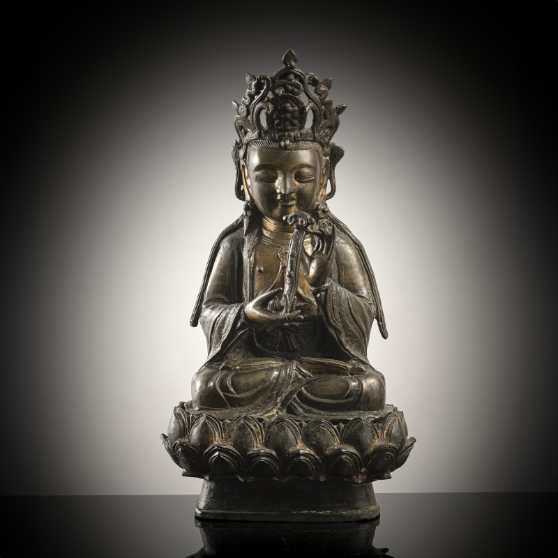 A bronze model of Guanyin on a lotus, holding a sceptre in his hands