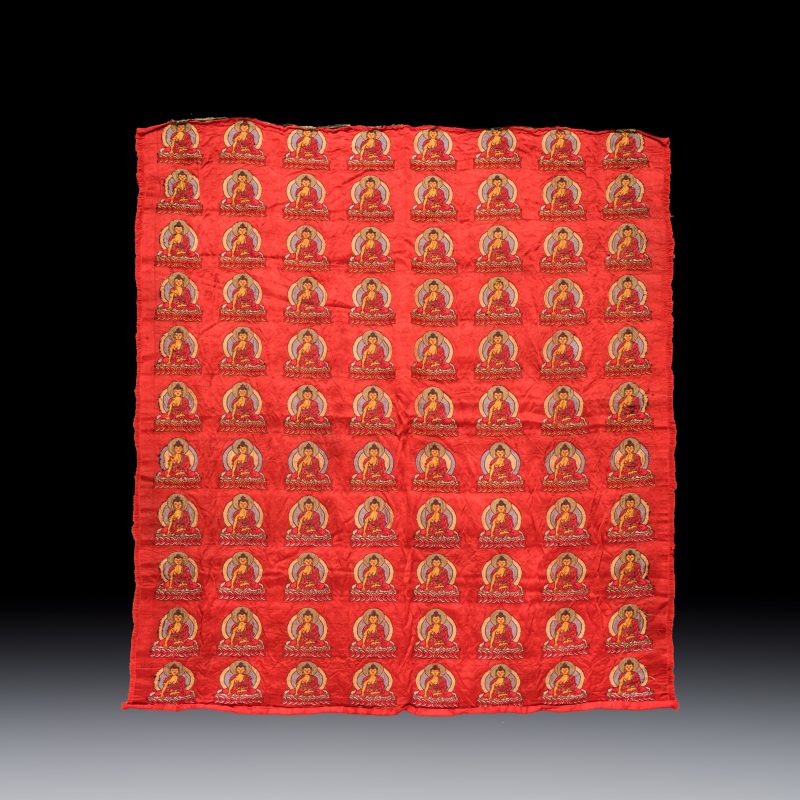 A Chinese red-ground brocade panel with seated Buddhas