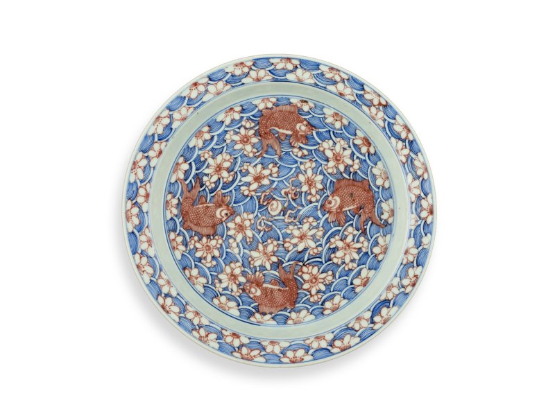 A rare underglaze-blue and copper-red-decorated 'carp’ charger, Mark and period of Kangxi | 清康熙　青花釉裏紅魚紋折沿大盤　《大清康熙年製》款