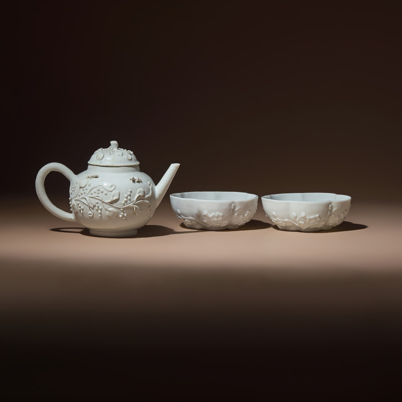 清中期 德化白瓷貼塑松鼠葡萄茶壺及茶碗一對 | A Chinese Blanc-de-Chine Molded Porcelain Covered Teapot and a Pair of Molded Floriform Bowls, 18th Century - 图1