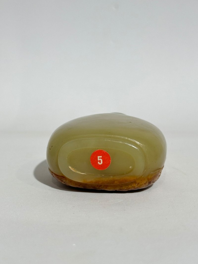清十八/十九世紀 卵石皮浮雕大師流派青玉帶皮巧雕松下童子紋鼻煙壺、珊瑚蓋 | A GREEN AND RUSSET JADE SNUFF BOTTLE - 图6