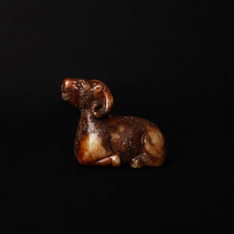 或為明 灰玉帶褐沁瑞羊擺件 | A Chinese mottled grey and russet jade carving of a ram, possibly Ming dynasty
