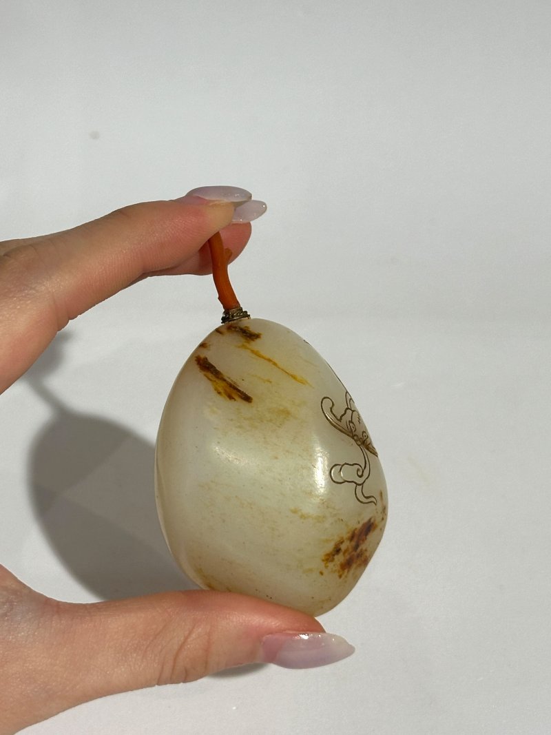 十九/二十世紀 白玉褐沁隨形祥雲蝠紋鼻煙壺、珊瑚蓋 | A WHITE AND RUSSET JADE PEBBLE-SHAPED SNUFF BOTTLE - 图3