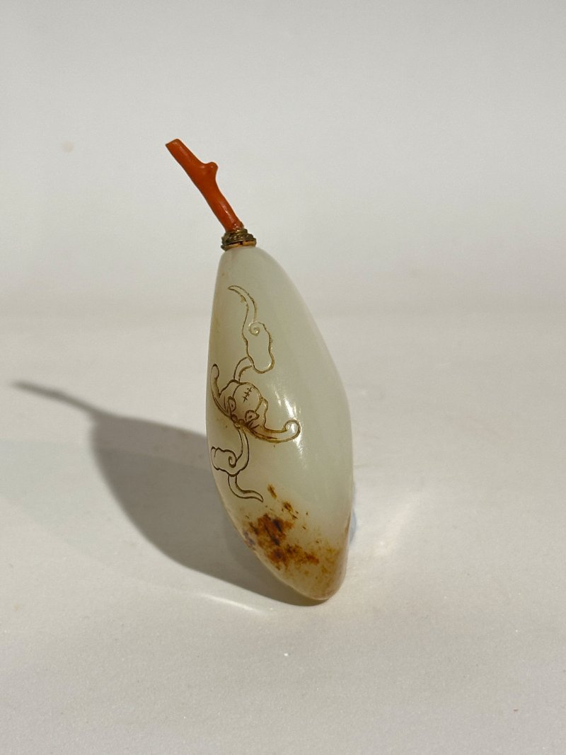 十九/二十世紀 白玉褐沁隨形祥雲蝠紋鼻煙壺、珊瑚蓋 | A WHITE AND RUSSET JADE PEBBLE-SHAPED SNUFF BOTTLE - 图7