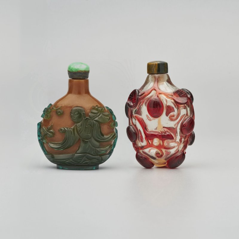清十九世紀 棕地套綠玻璃僧侶持蓮紋、透明地套紅玻璃松鼠葡萄紋鼻煙壺二件 | A GREEN OVERLAY BROWN GLASS 'MONK HOLDING A LOTUS' AND A RED OVERLAY GLASS 'SQUIRREL' SNUFF BOTTLE - 图1