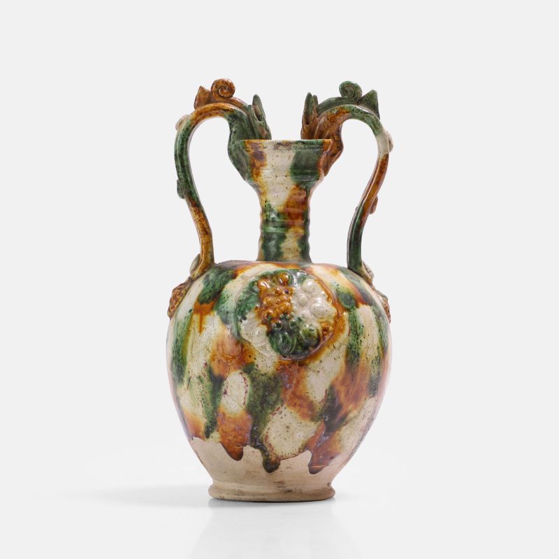 唐 三彩贴花弦纹双龙耳盘口尊 | A Chinese sancai-glazed two-handled 'amphora' vase Tang dynasty (618-907), the well-potted ovoid body applied with medallions and a pair of dragons - 图1