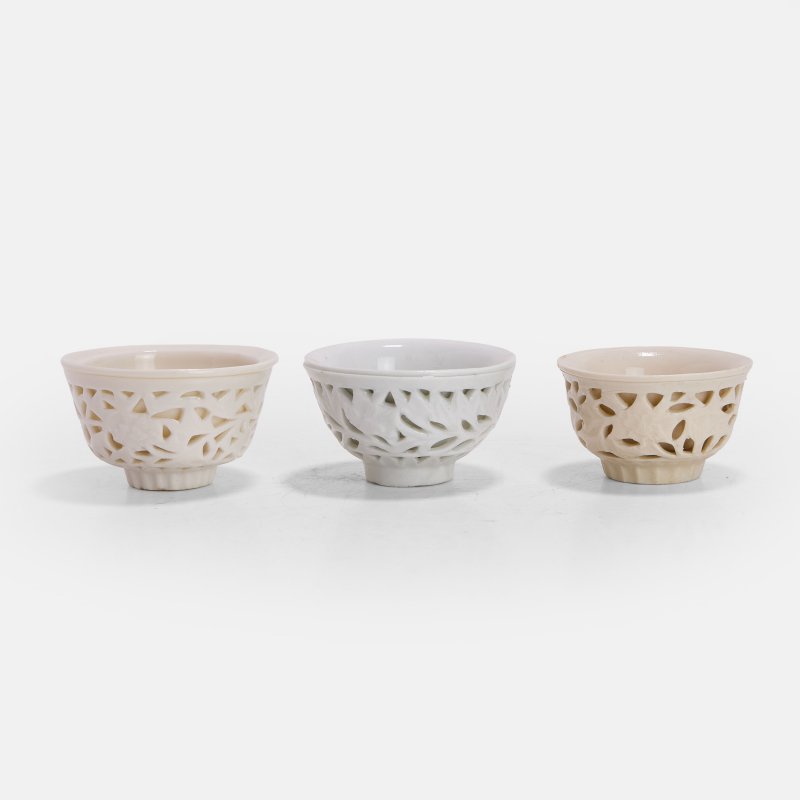 十七世纪 德化窑白釉镂雕缠枝花卉纹杯 一组三件 | Three Chinese blanc de Chine 'linglong' reticulated cups 17th century, the outer walls moulded with sections cut through